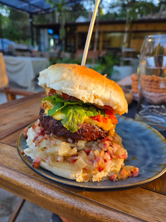 Ranch Burger, 200 gr de carne Brangus, Salsa de queso cheddar, cebolla caramelizada, rucula, tomates cherry y ajos confitados, panceta y huevo frito